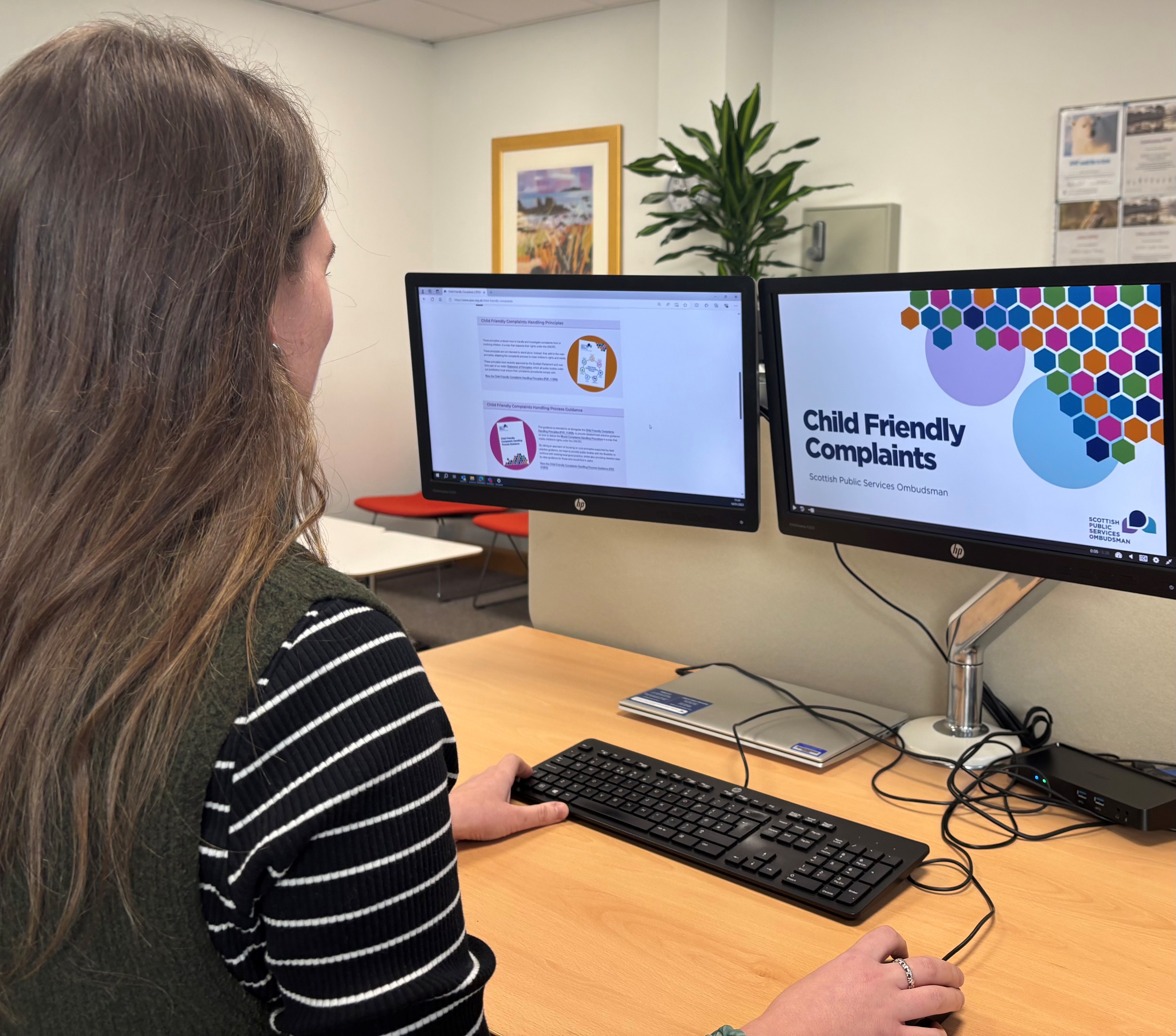 A woman sits at a computer completing the online child friendly complaints training.